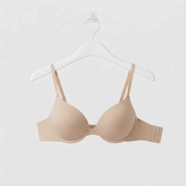 Nude t-shirt bra hanging on a white hanger at Pixosum store